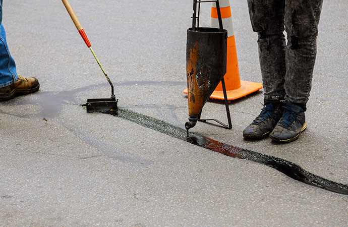 Professional worker repairing asphalt crack