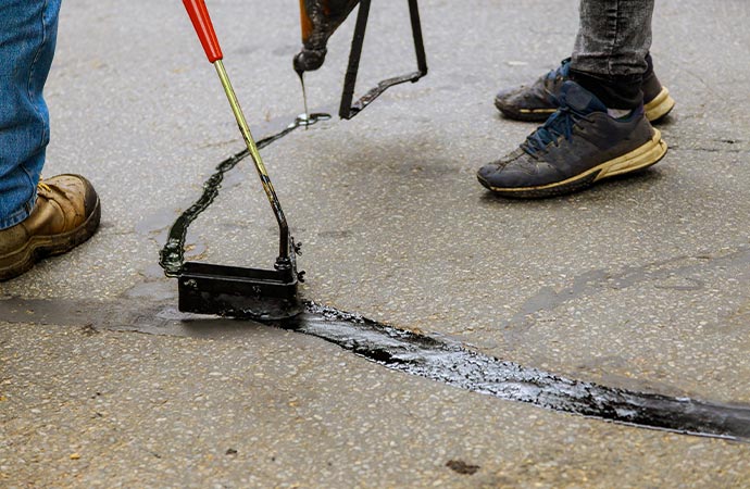 Professional worker repairing asphalt crack