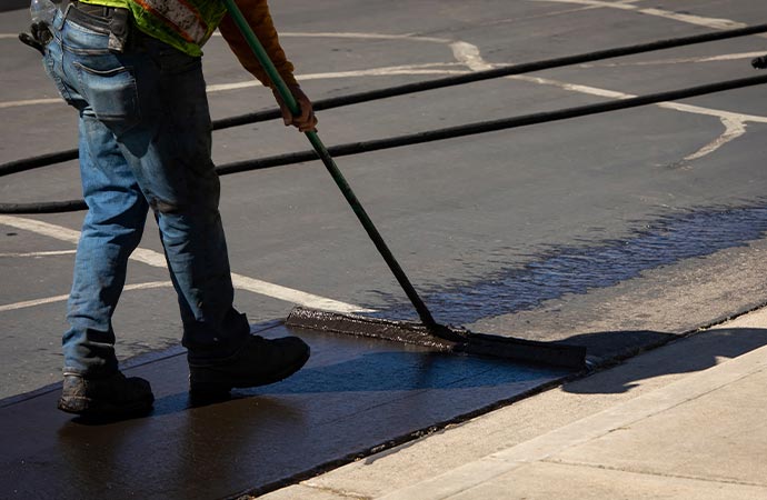 Worker conducting asphalt resurfacing for road maintenance.