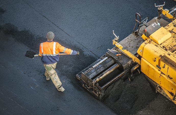 Workers engaged in asphalt road repair for enhanced durability.